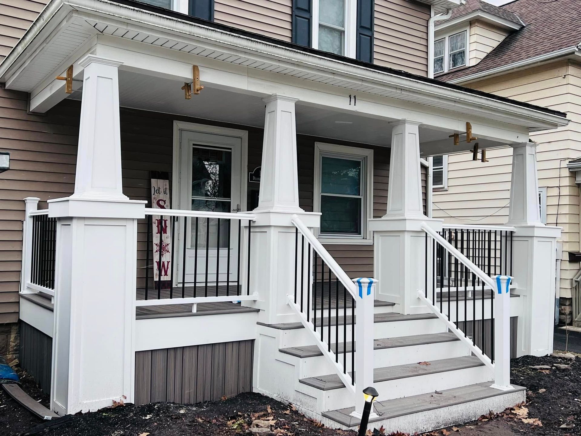 The front porch of a house with stairs and a railing.