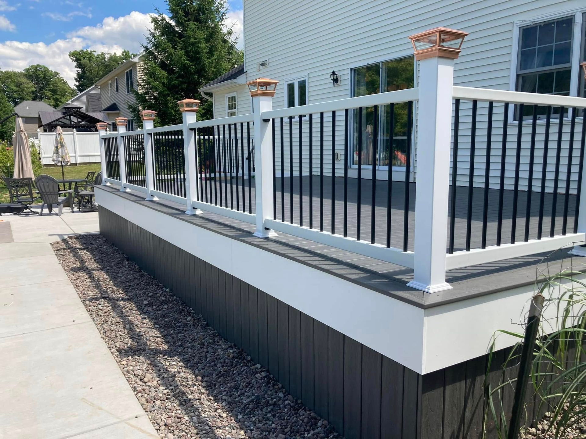 A white deck with a black railing is sitting next to a house.