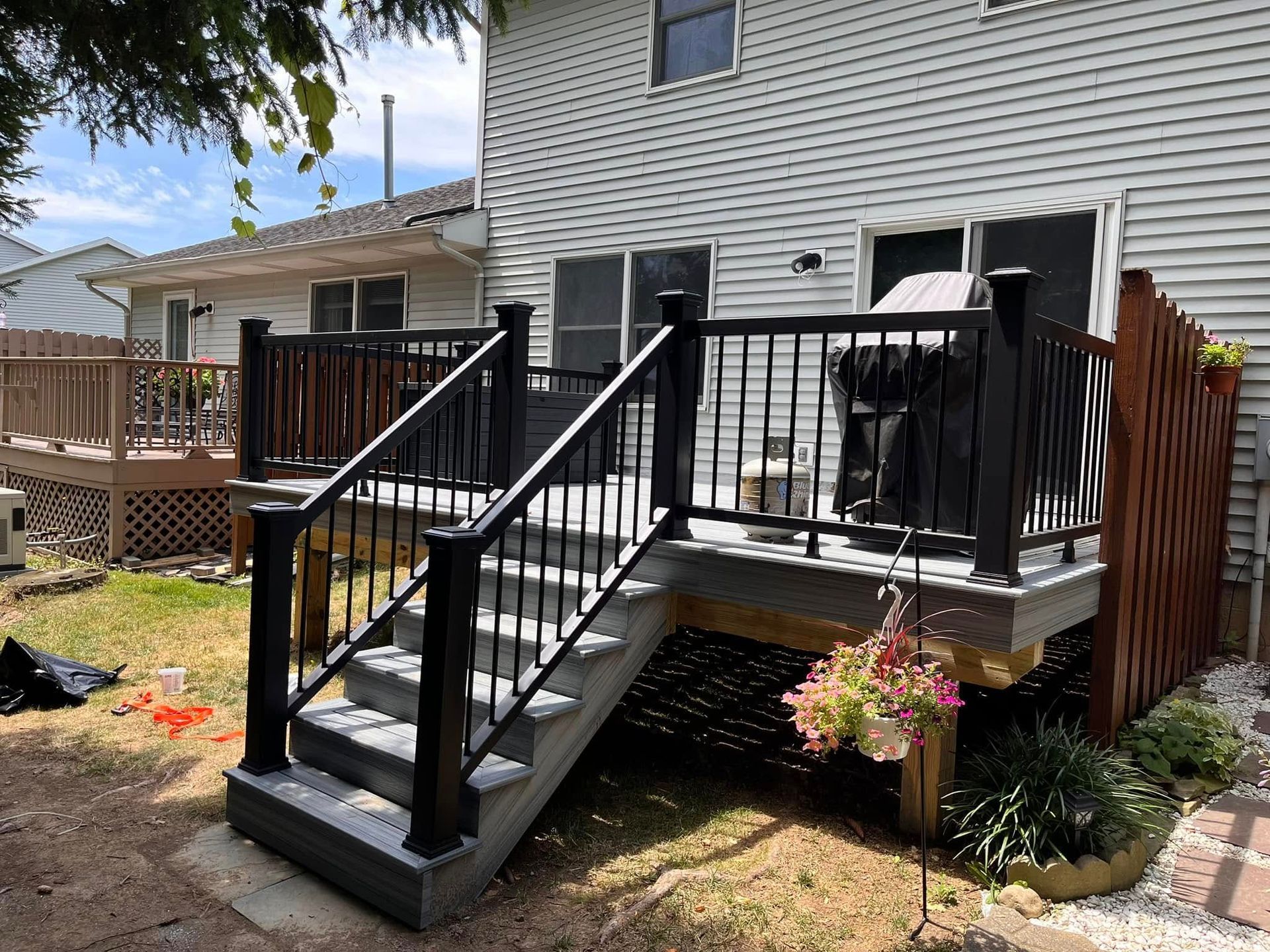 A deck with stairs leading up to it is in the backyard of a house.