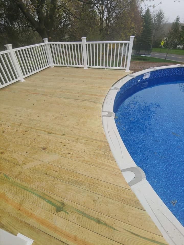 A wooden deck next to a swimming pool with a white railing.
