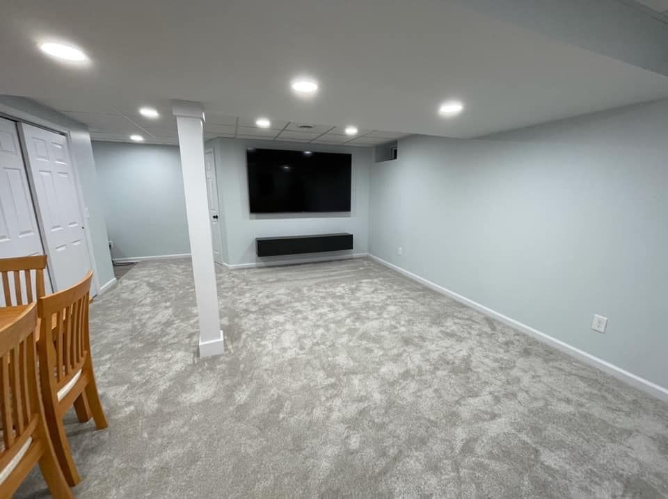 An empty basement with a flat screen tv on the wall.