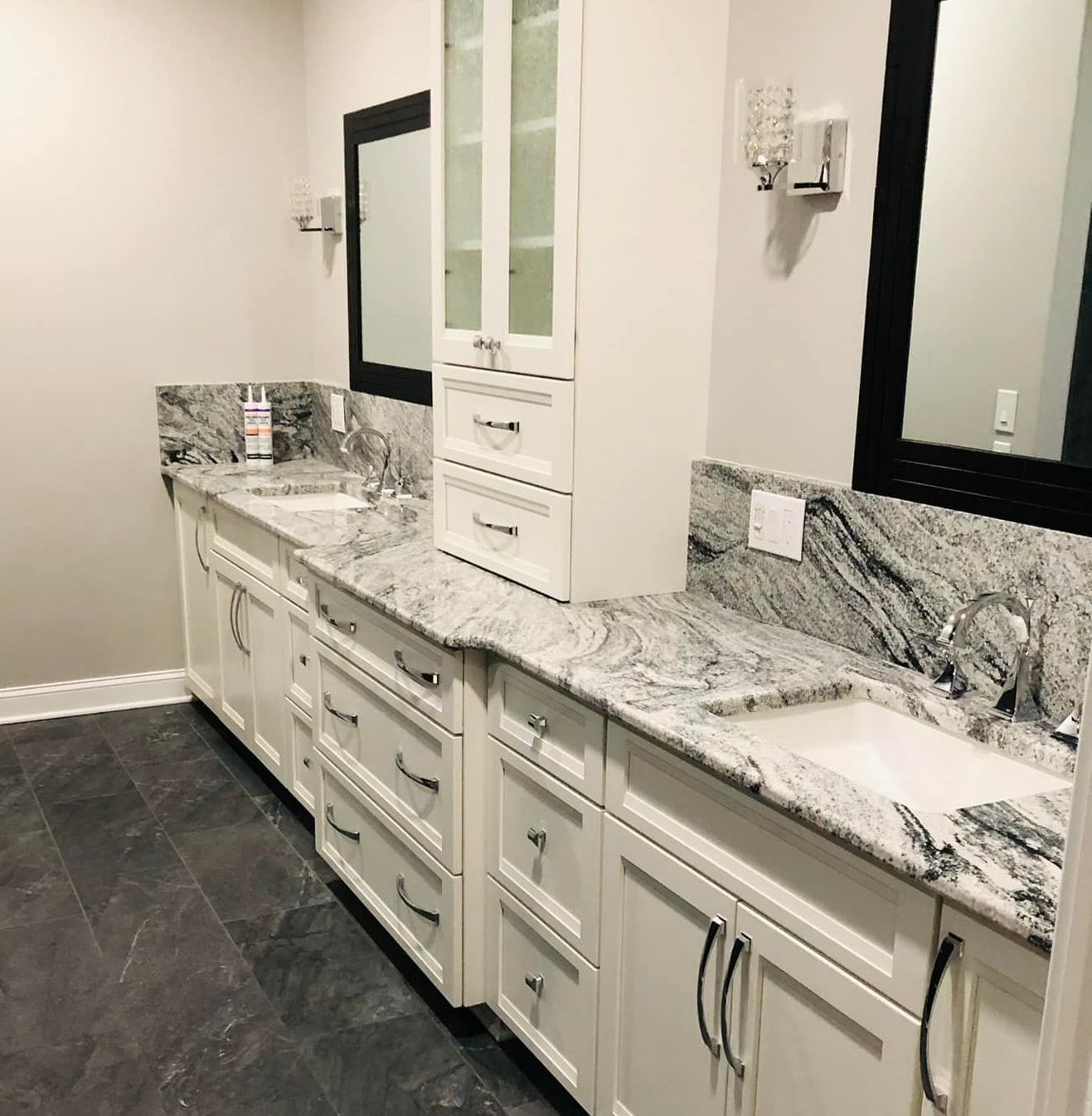 A bathroom with white cabinets and granite counter tops