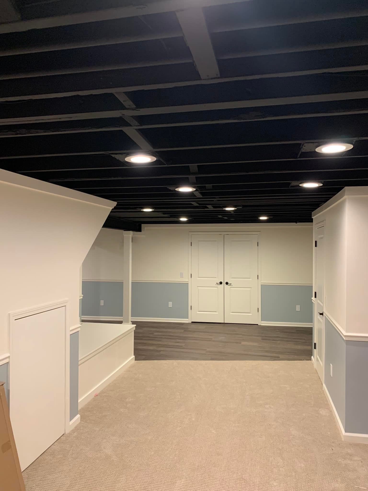 An empty basement with a black ceiling and white walls.