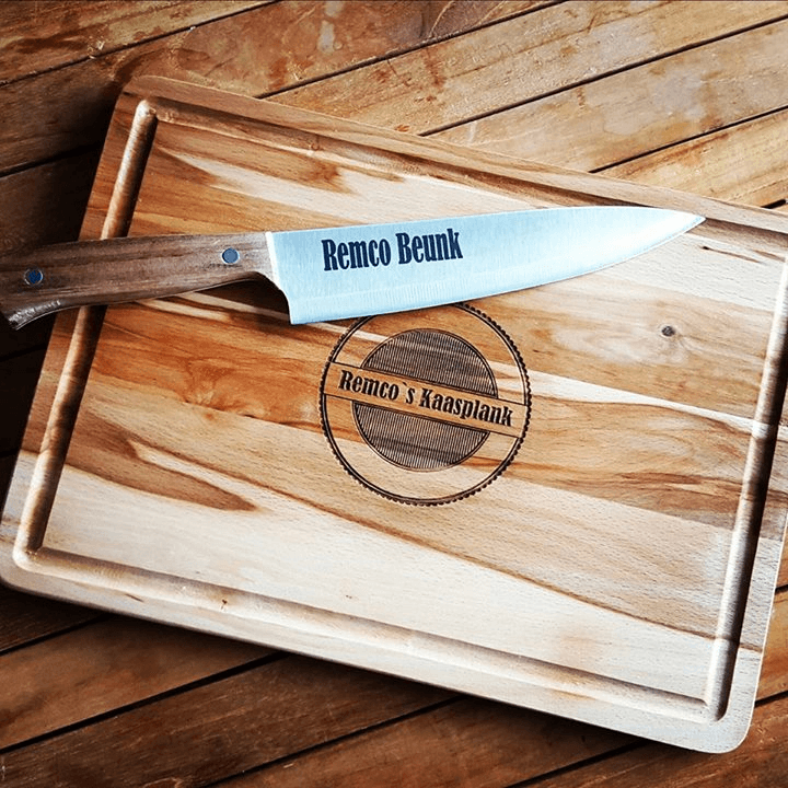 Houten snijplank met een koksmes en wit lemmet op een houten tafel, met het opschrift