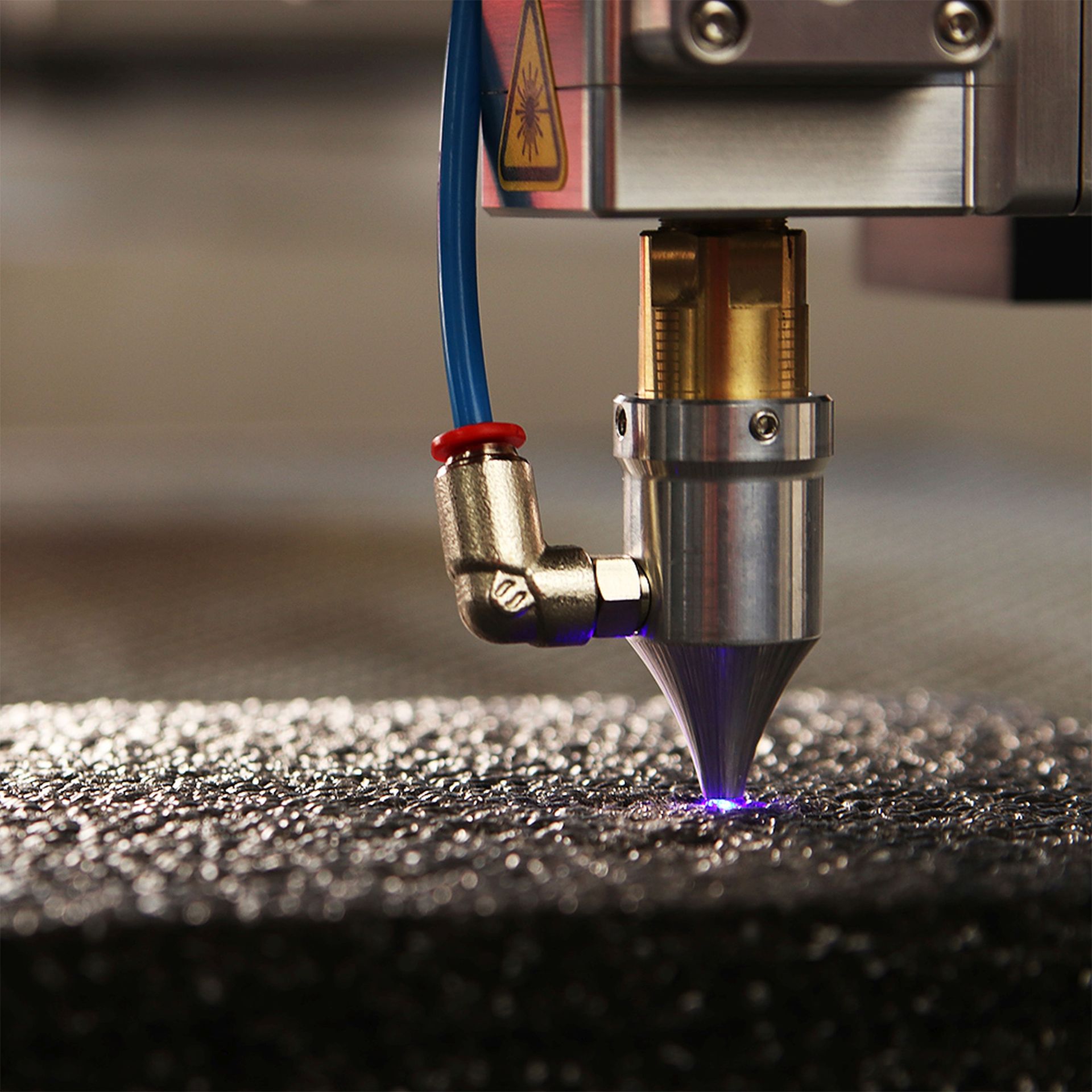 De lasersnijkop graveert een metalen oppervlak met een paarse gloed.