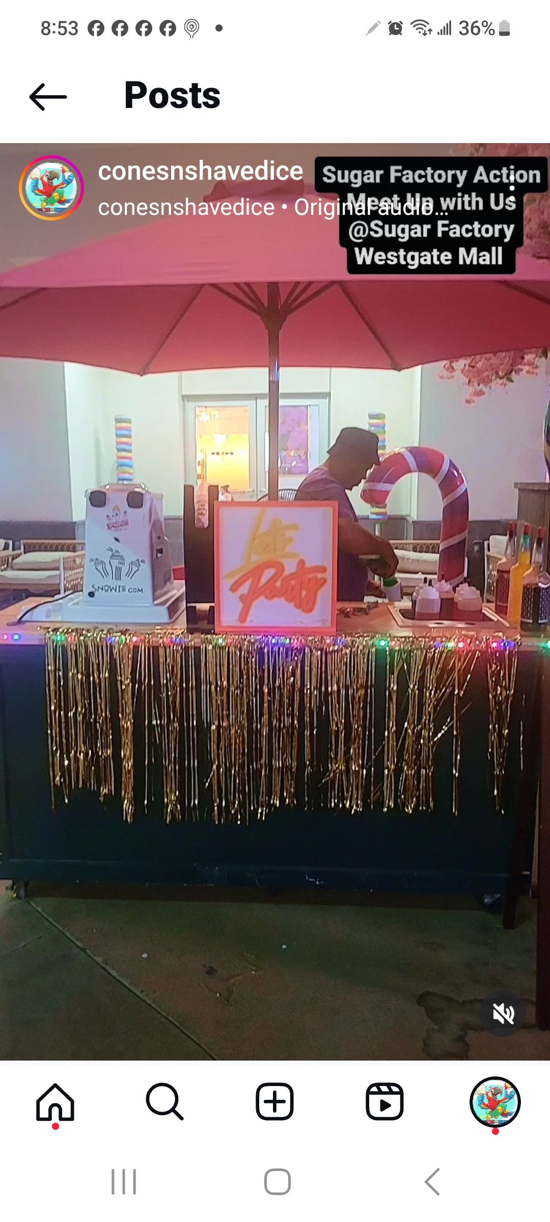 A decorated table with a person behind it under a red umbrella. The table has a painting, candy cane, and a cake.