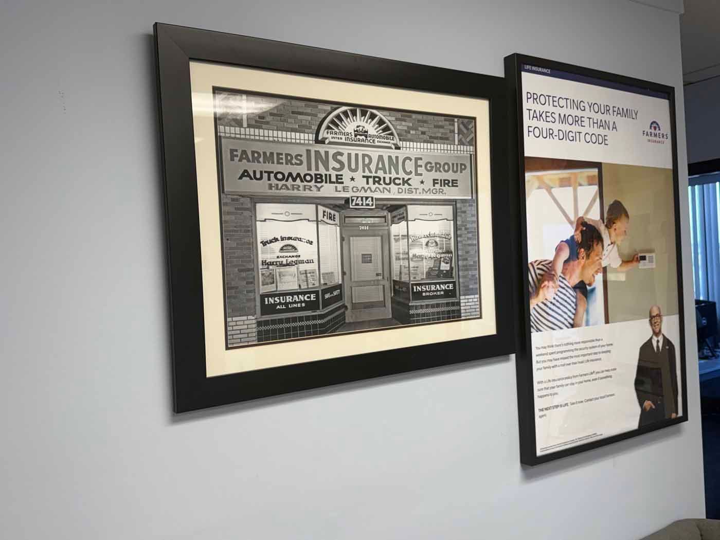 Framed vintage insurance ad and poster on a gray office wall