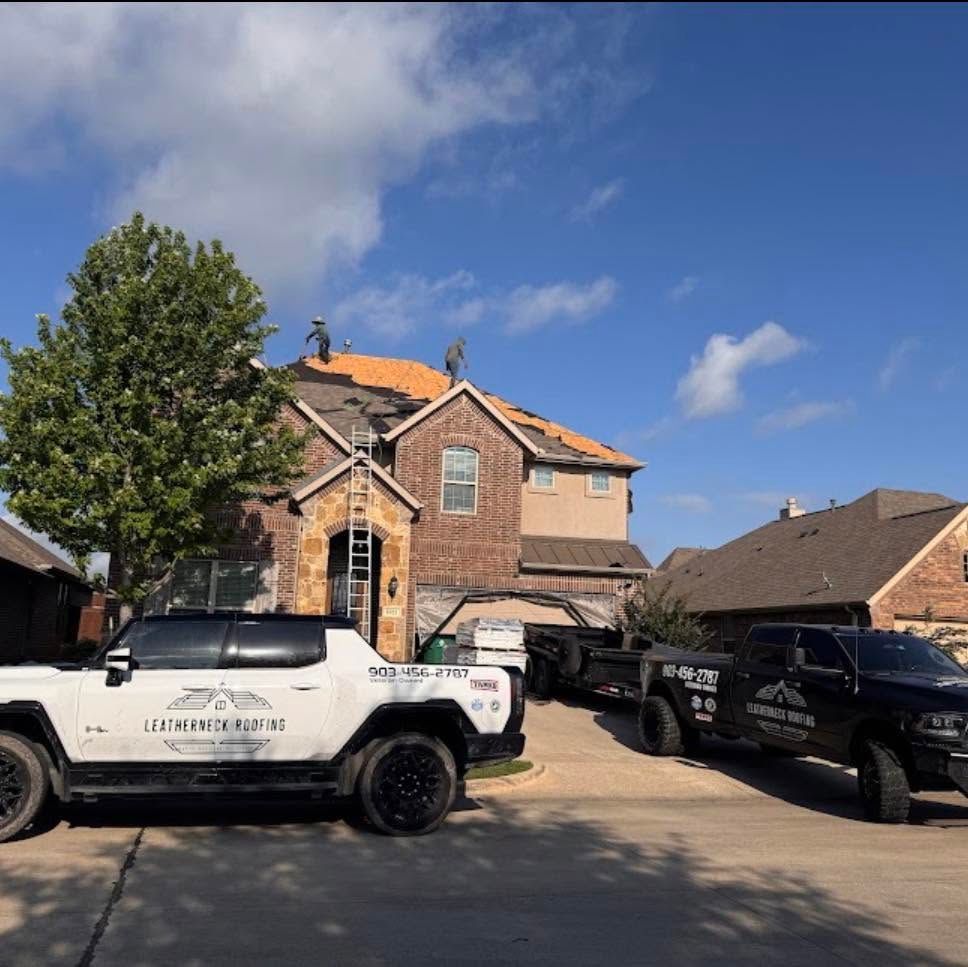 Two pickup trucks parked outside a brick house on a sunny suburban street