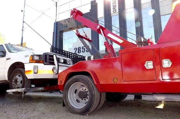 Una grúa roja está remolcando un coche blanco.