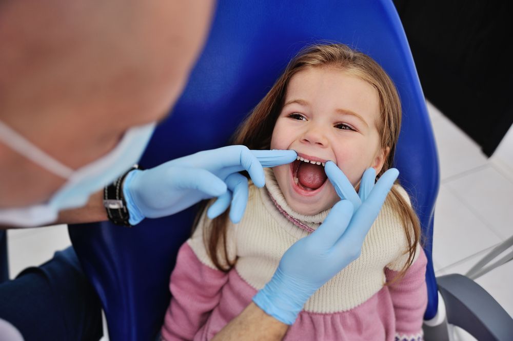 A little girl is having her teeth examined by a dentist.