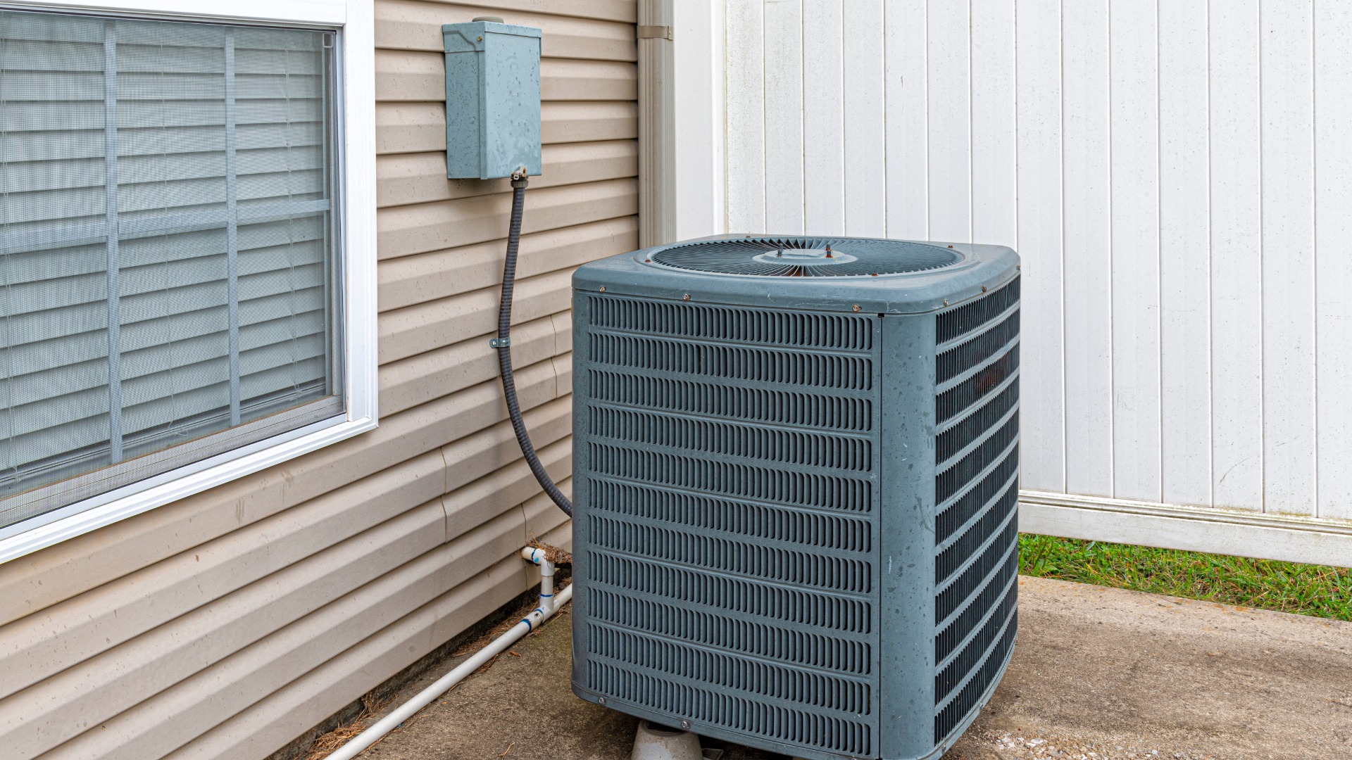 Outdoor air conditioning unit beside a house window and electrical box