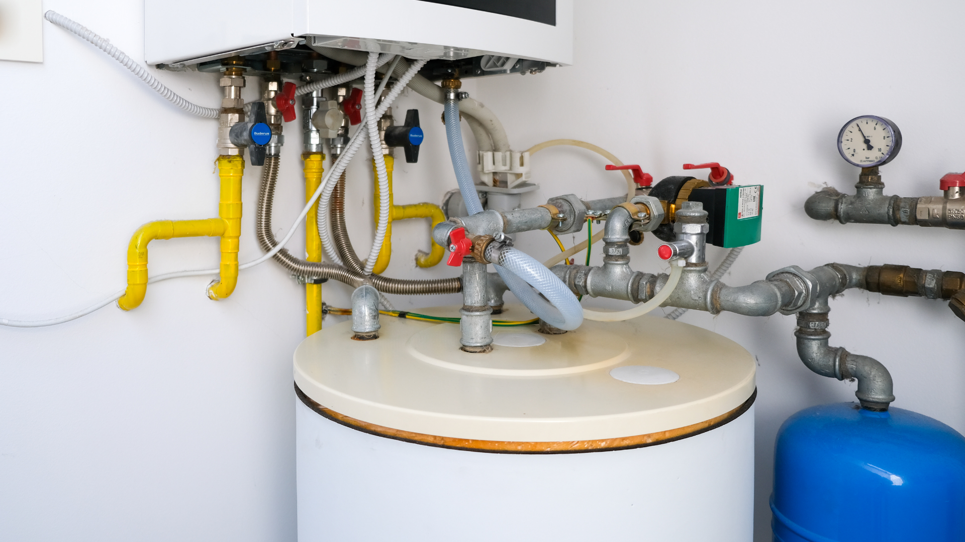Water heater and plumbing valves with yellow and gray pipes in a utility room