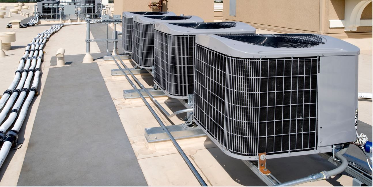 Solar panels and battery storage units mounted on a brick wall with electrical wiring above them