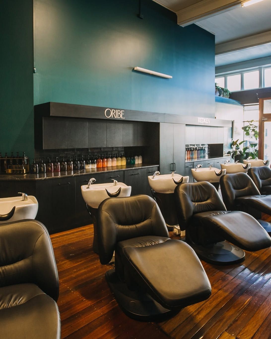 Salon With Black Reclining Chairs, Wood Floors, and Teal Walls — Air Hair Studio in Toowoomba City, QLD