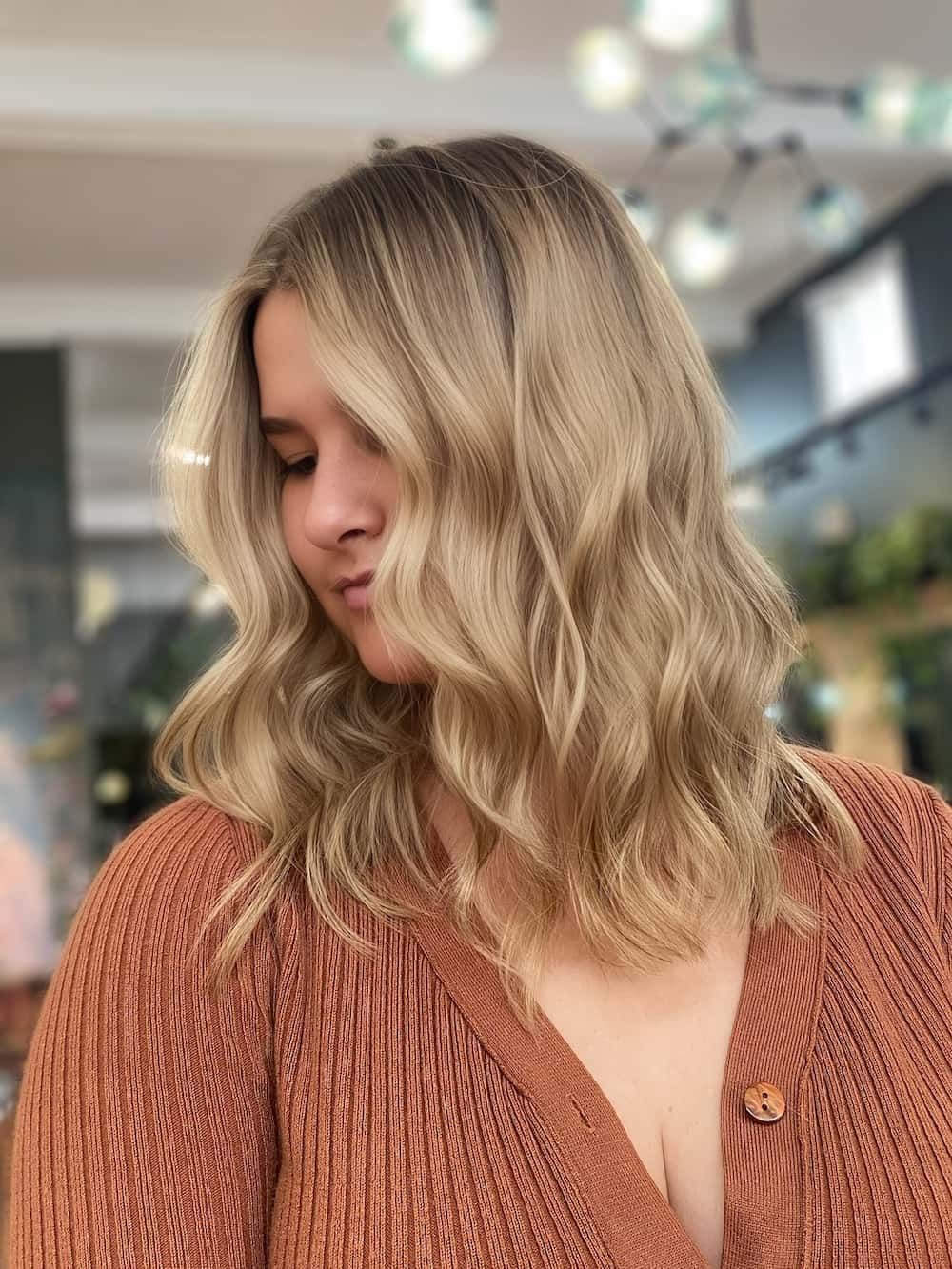 A Woman With Blonde Hair is Wearing a Brown Sweater — Air Hair Studio in Toowoomba City, QLD