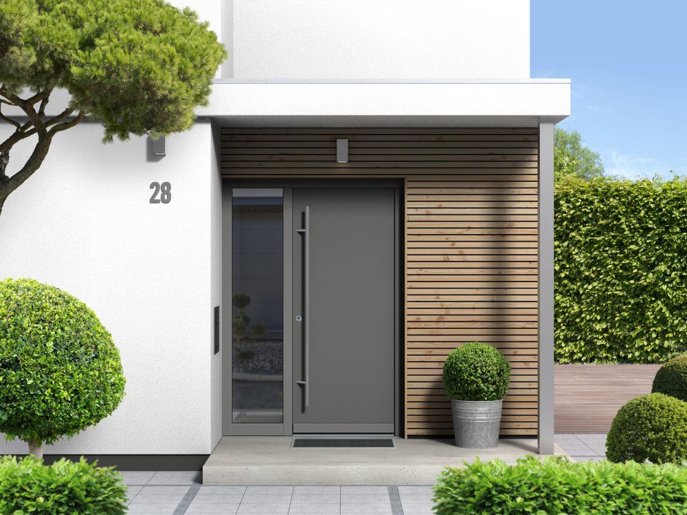 The front door of a house with a gray door and a tree in front of it.