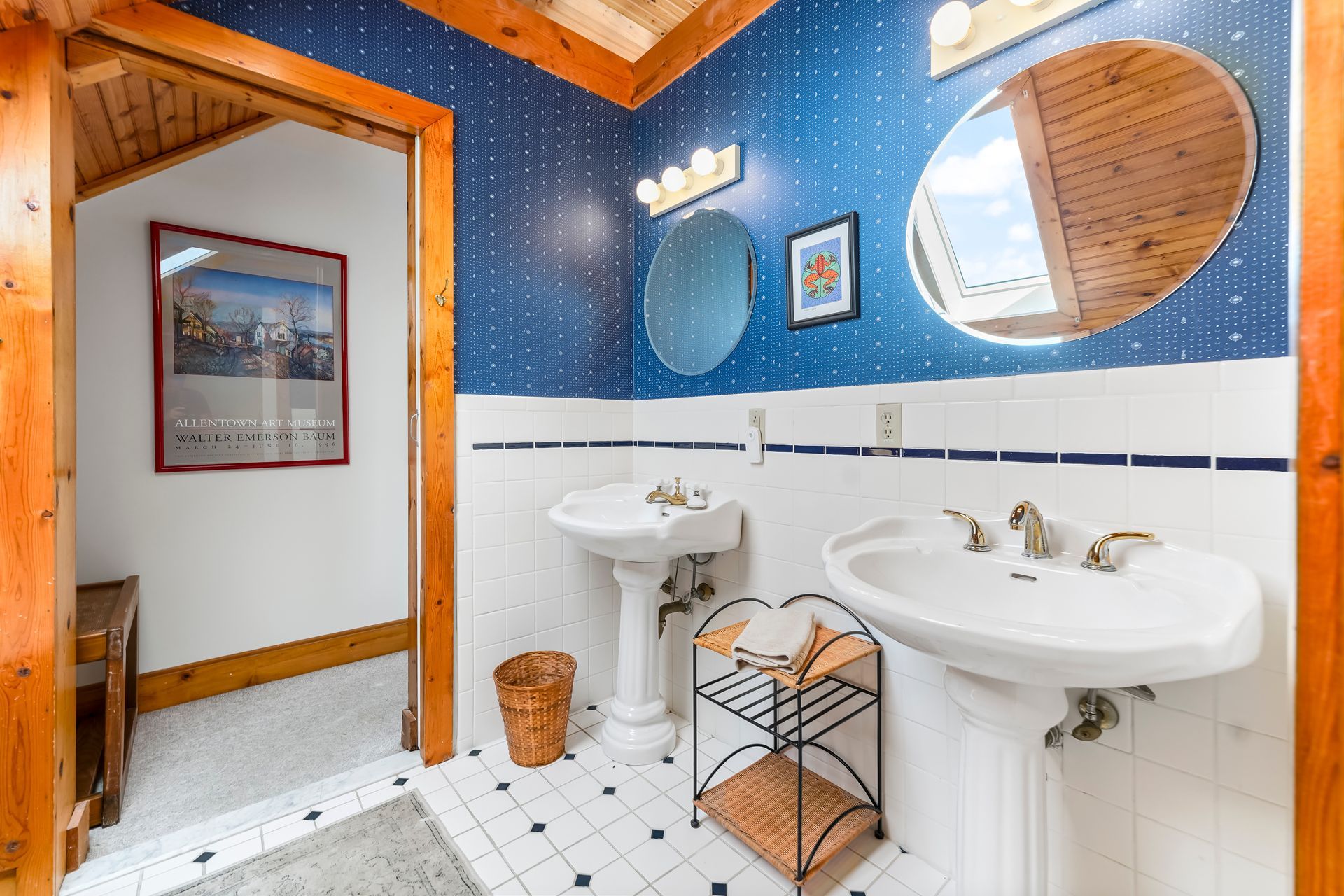 Bright bathroom with blue wall, white sink, mirror, and open doorway to a bedroom.