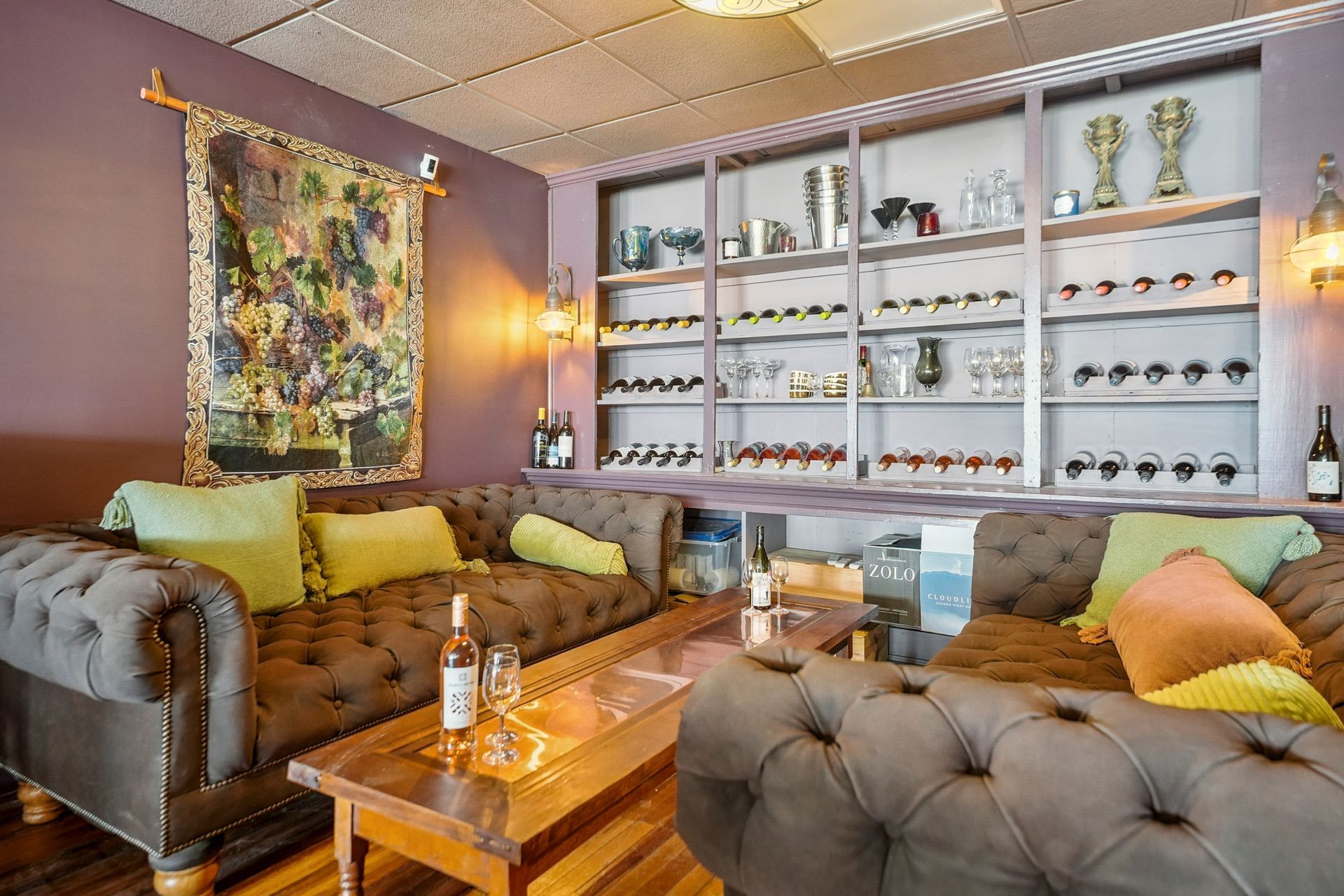 Stylish living room with tufted sofas, wooden coffee table, and glass display shelves on purple walls