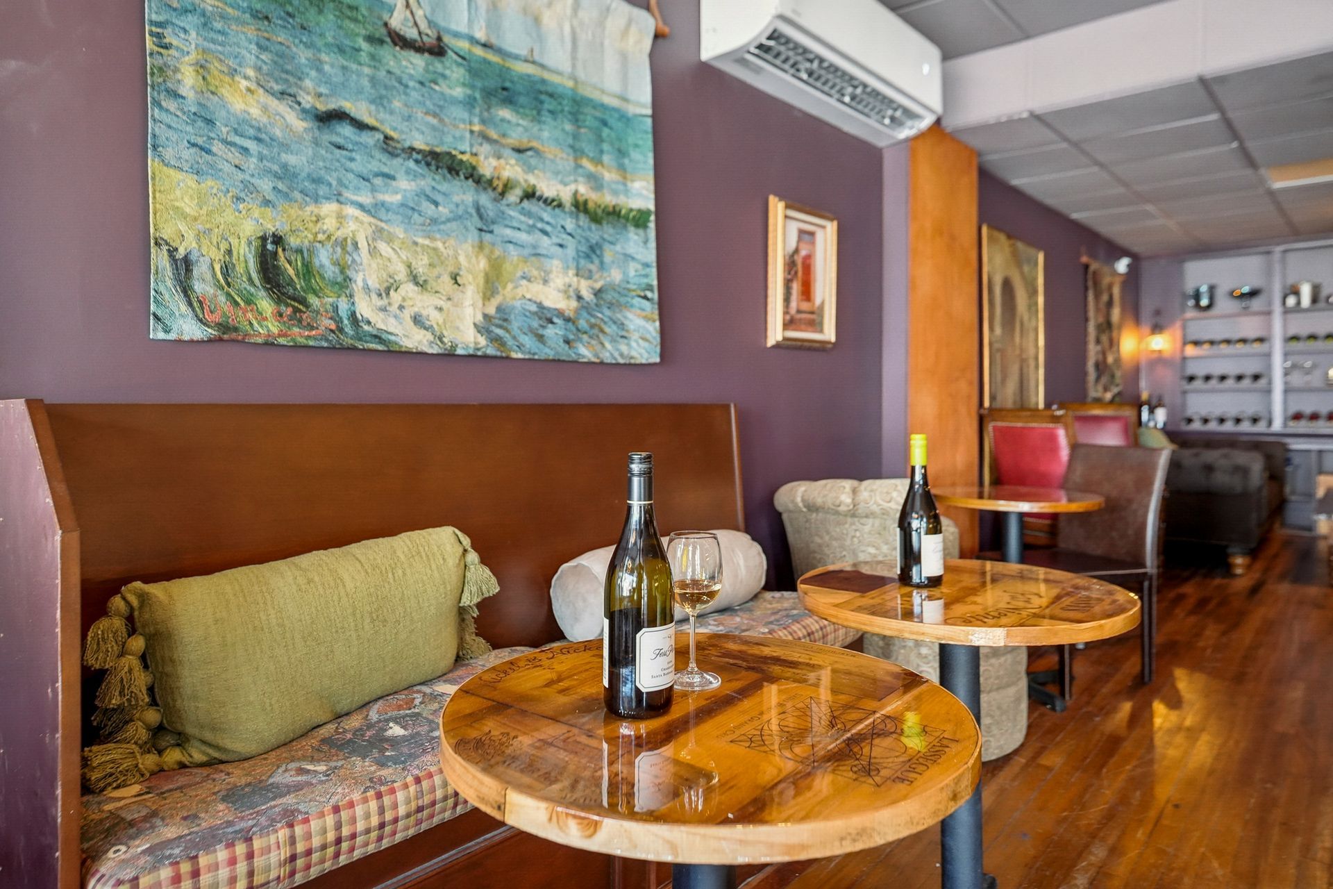 Cozy lounge with wooden tables, cushioned bench seating, wall art, and warm lighting