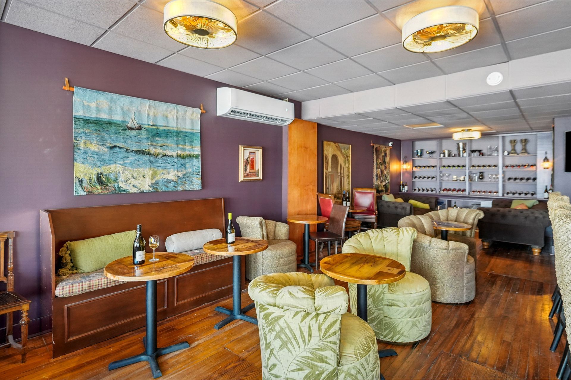 Cozy lounge with green chairs, wooden tables, booth seating, and warm lighting in a retro-style room