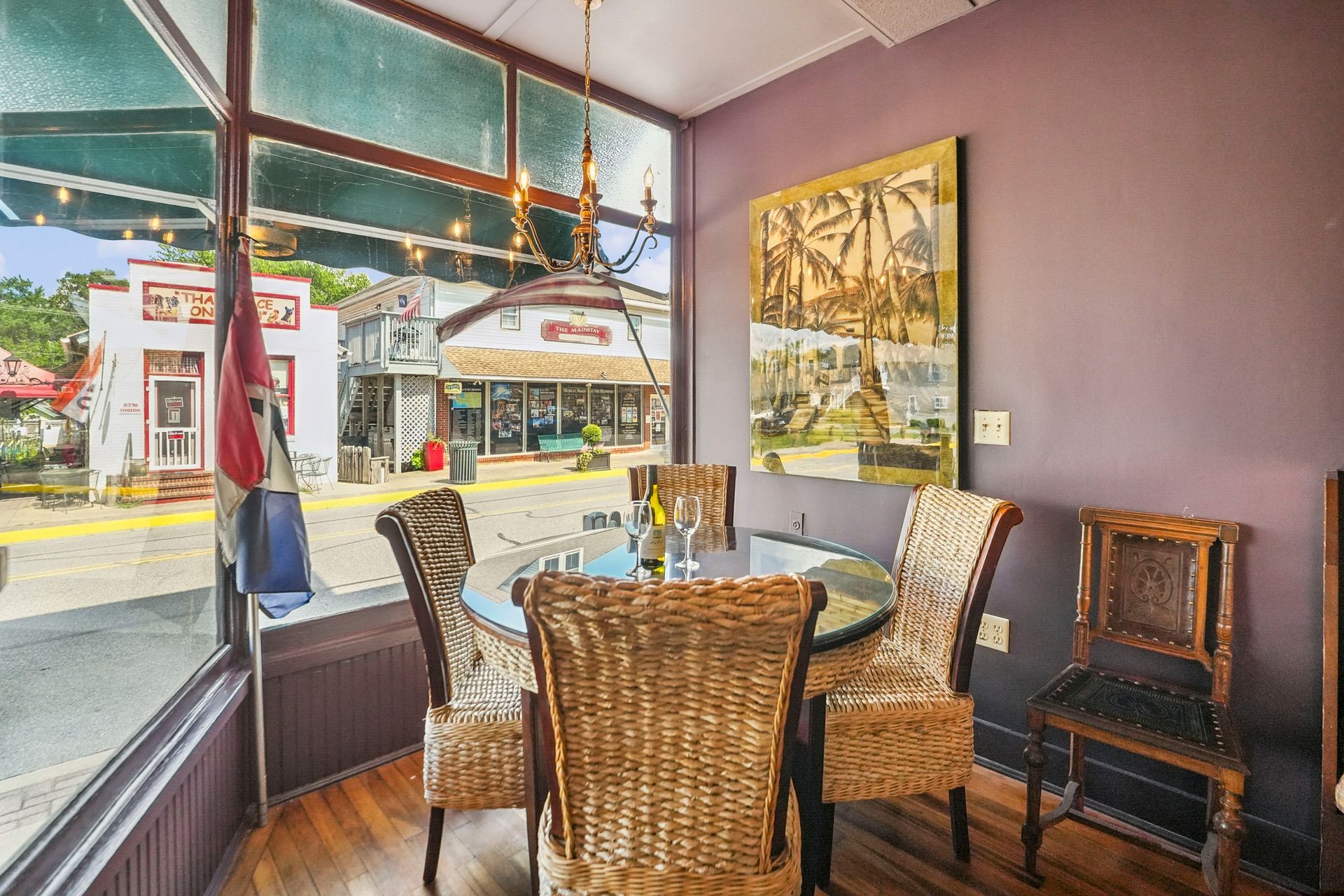 Cozy café corner with wicker chairs, round table, and large windows overlooking a street.