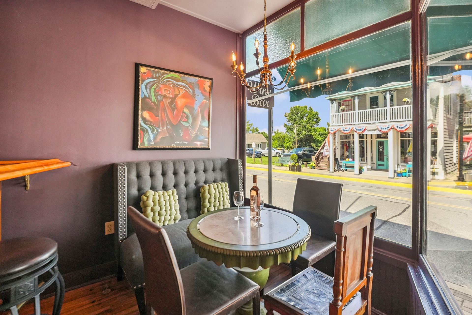 Cozy restaurant corner with round table, dark booths, wall art, and a large window overlooking the street