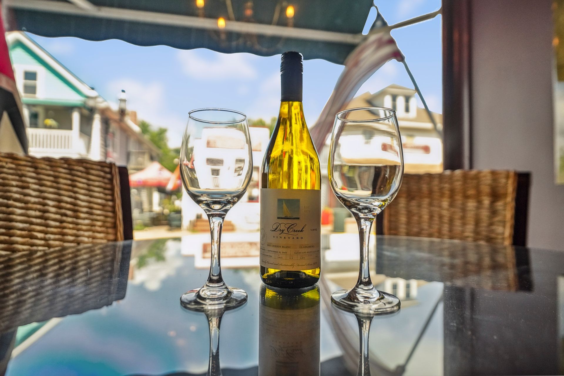 Wine bottle and two glasses on a patio table with a harbor view in the background