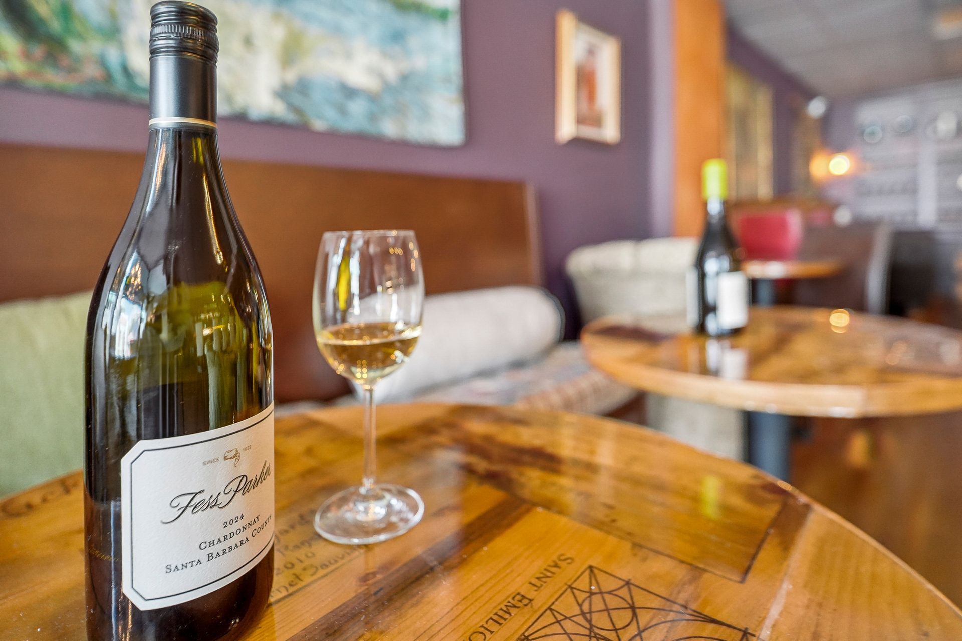 Wine bottle and glass on a wooden table in a cozy restaurant lounge