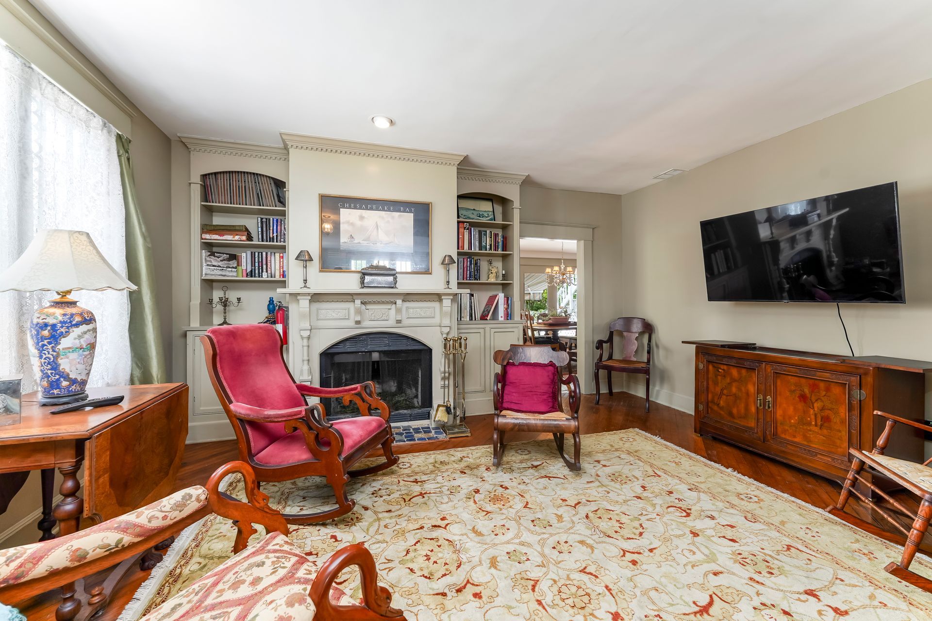 Elegant living room with fireplace, pink chairs, patterned rug, and wall-mounted TV