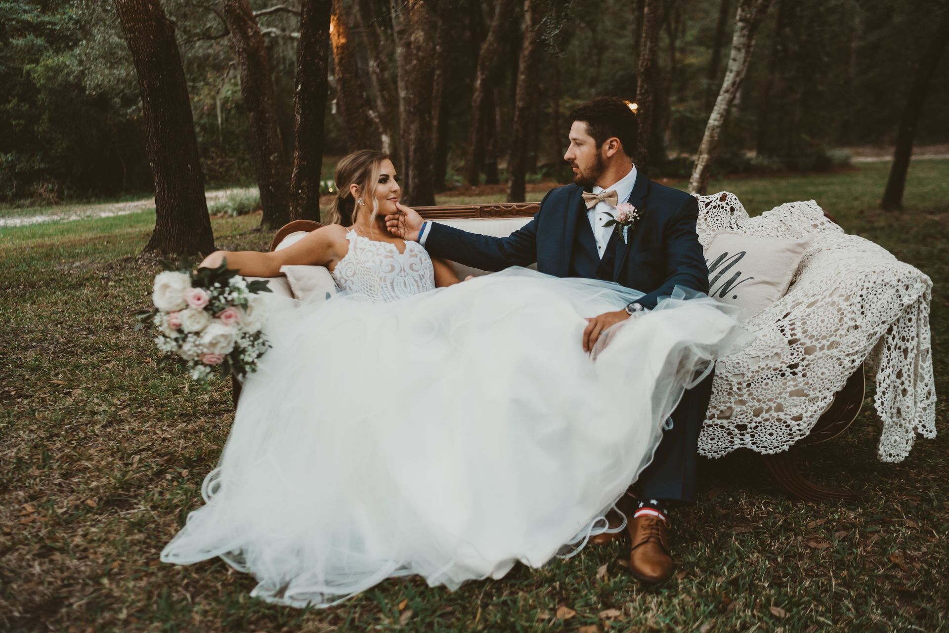 bride and groom sitting on antique couch outdoors