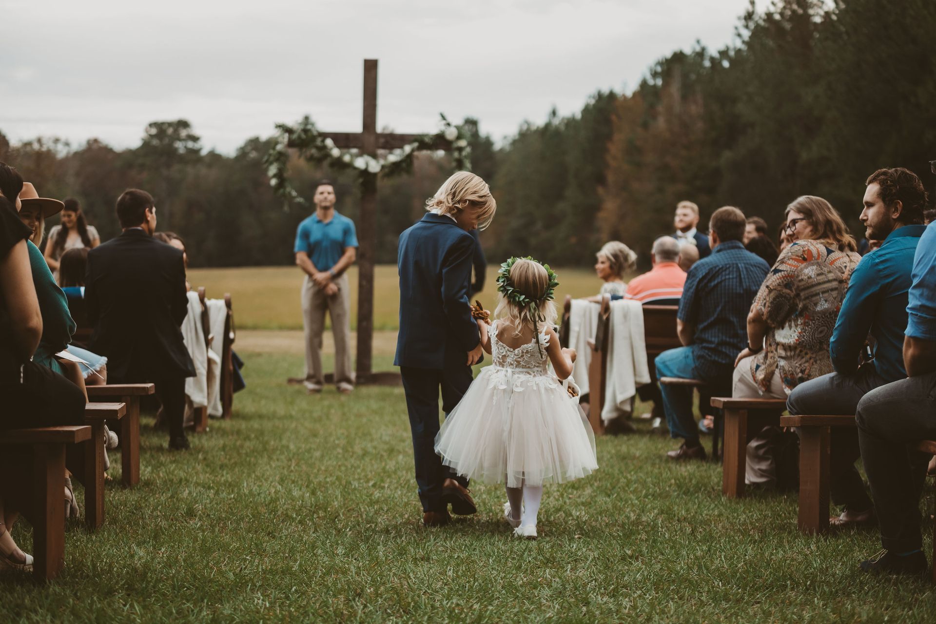 ring bearer and flower girl walking down aisle in outdoor wedding