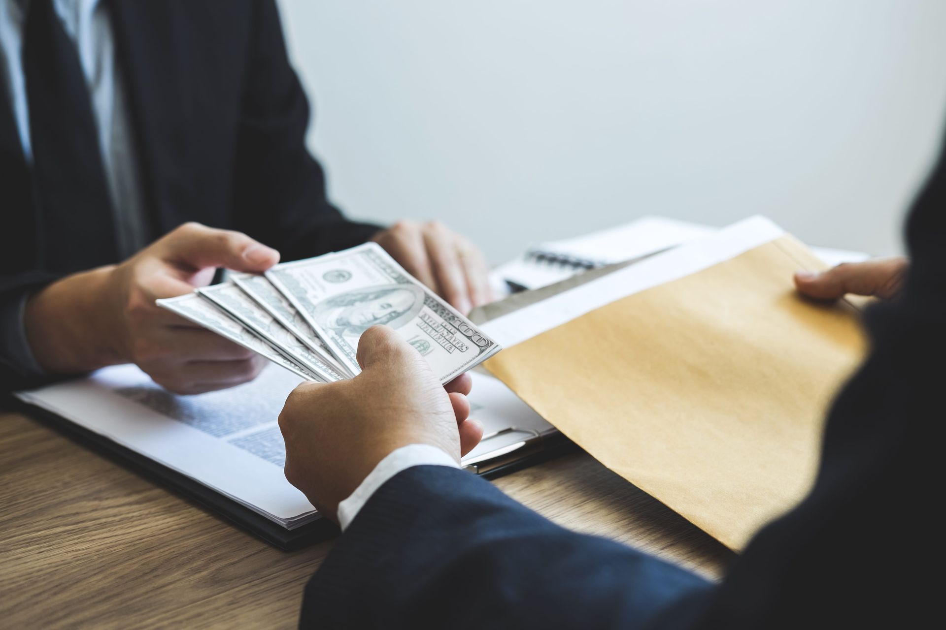 People exchanging cash and documents at a desk in an office meeting