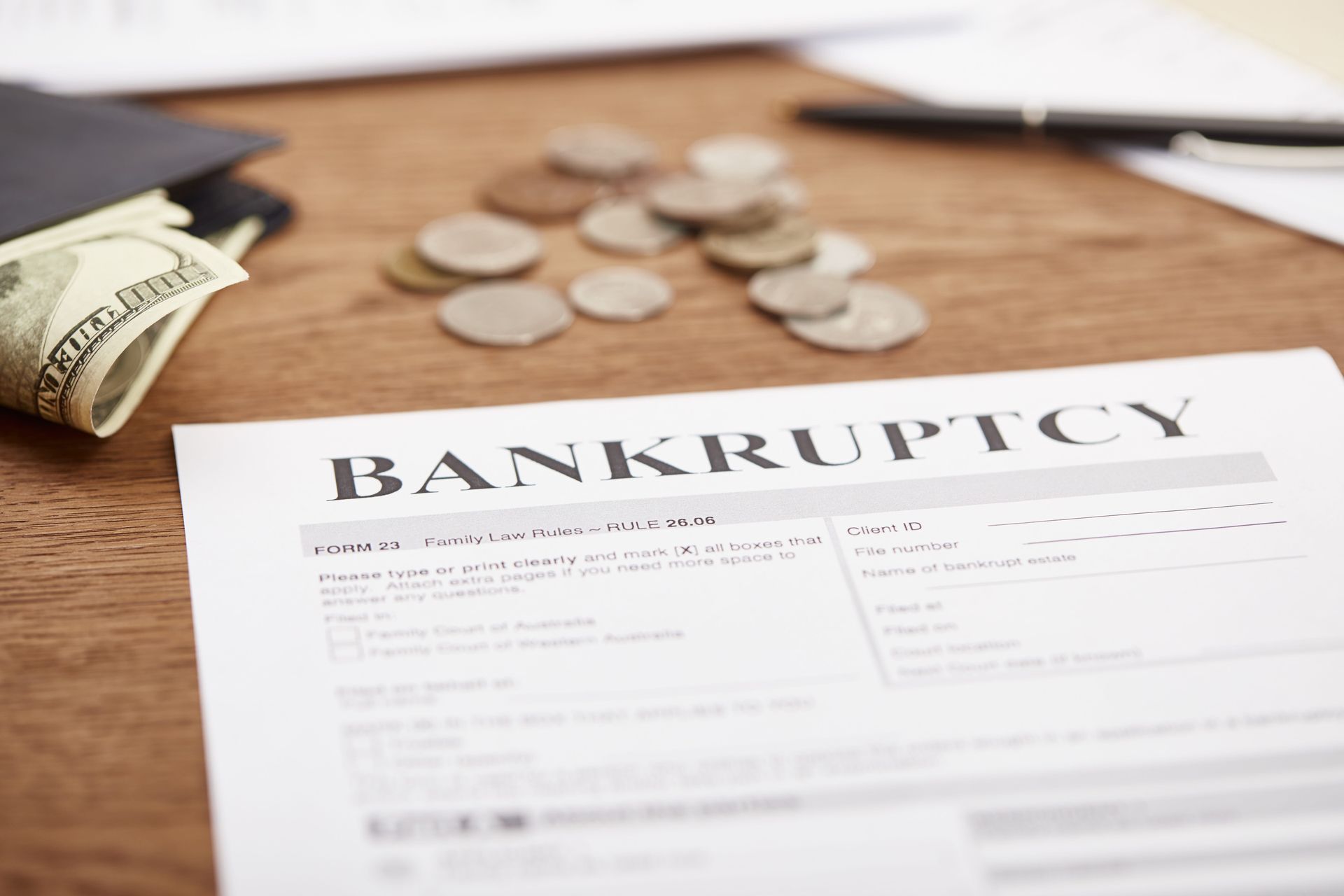 Bankruptcy form on a desk with scattered coins and a tipped-over wallet
