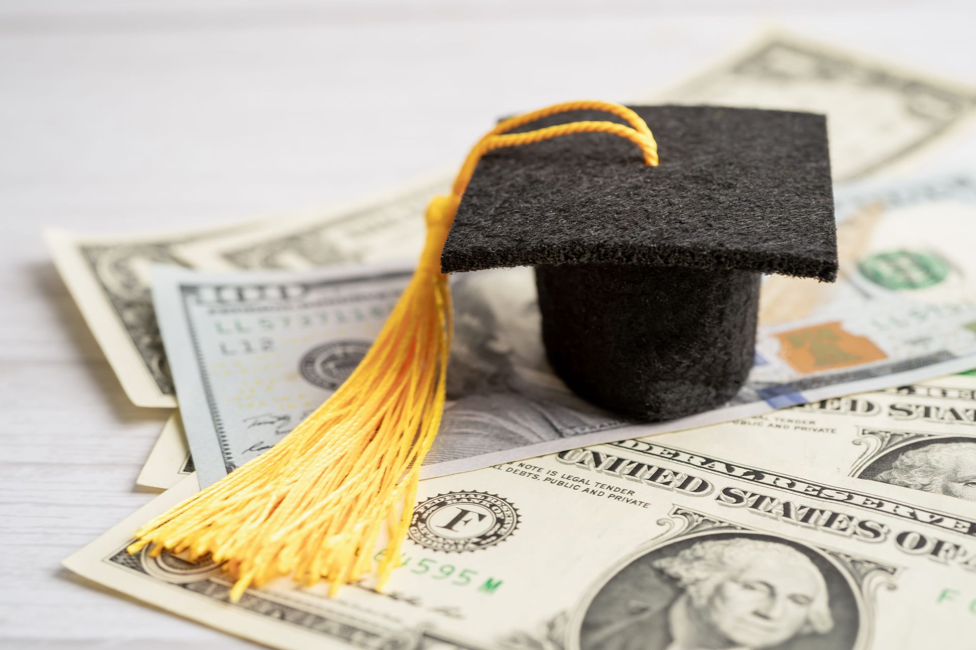 Graduation cap with gold tassel on US dollar bills