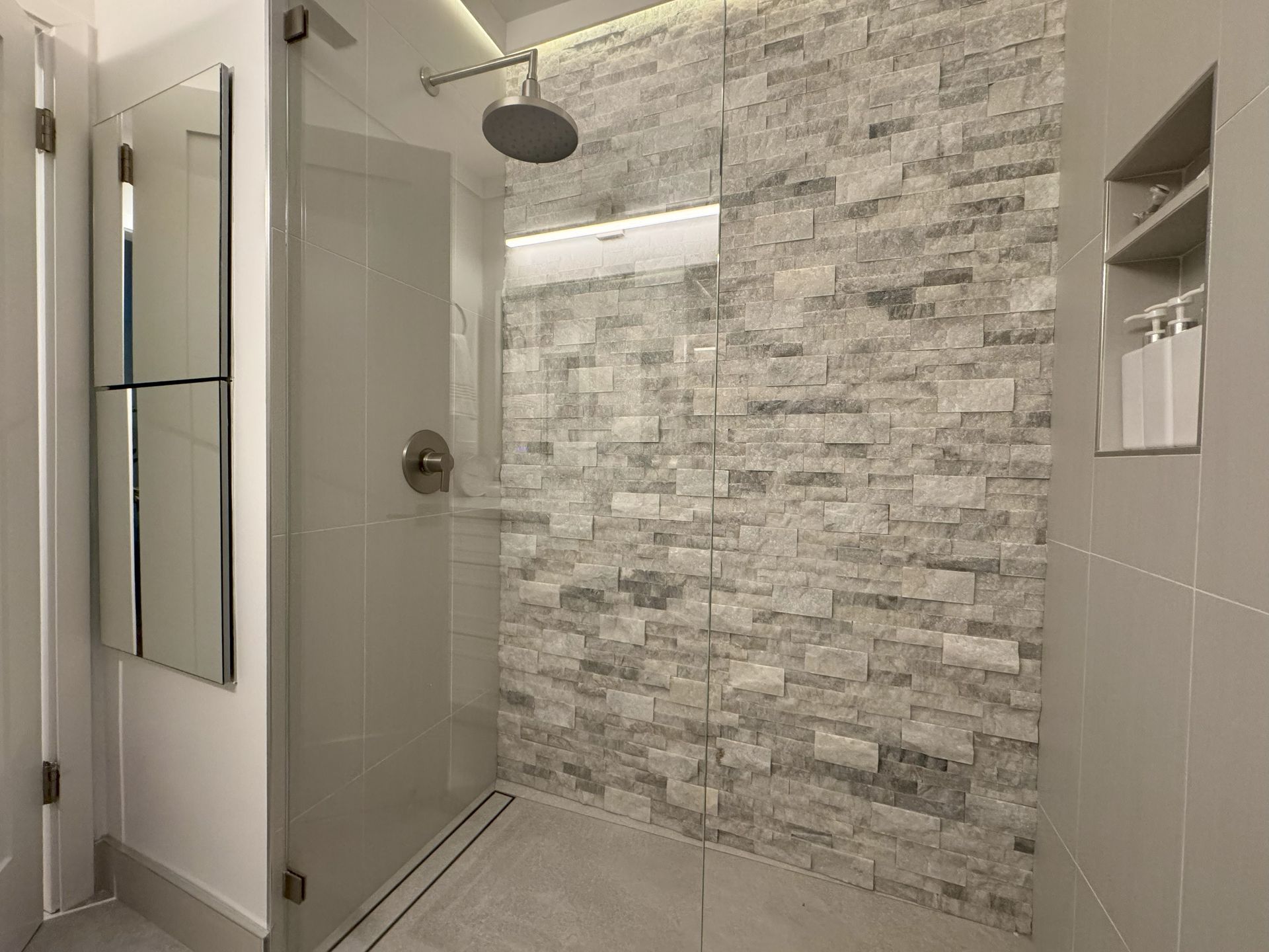 Modern bathroom with stone tile shower and glass door.