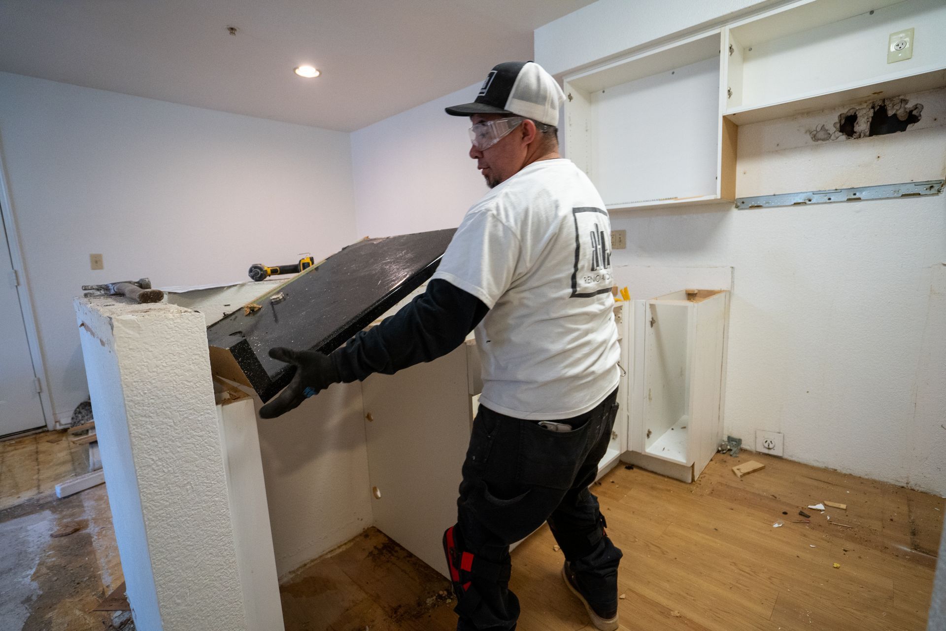 Man removing a countertop in a kitchen renovation.