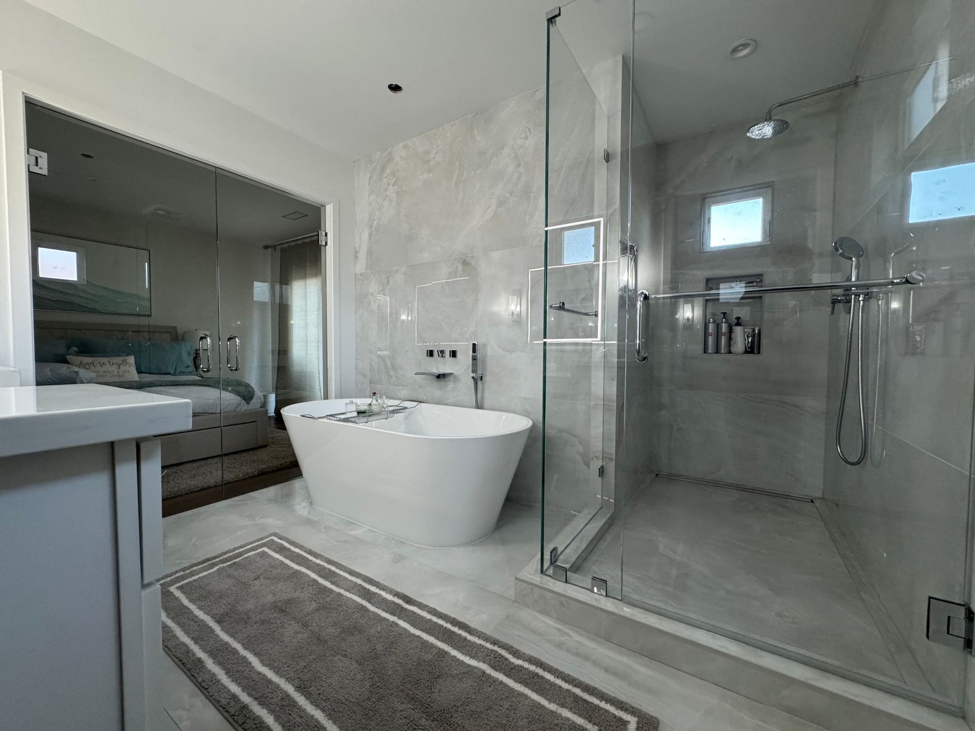 Modern bathroom with freestanding tub, glass shower, vanity, and gray rug