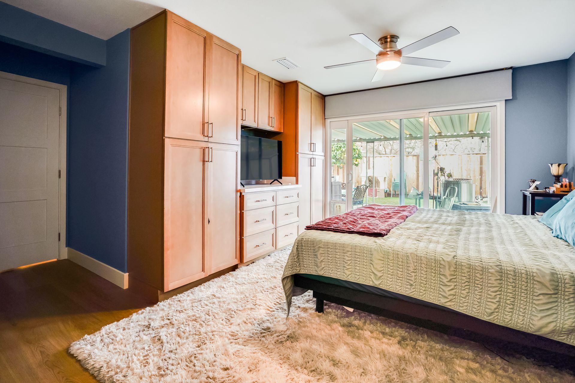 Bedroom with wooden cabinets, TV, bed, and sliding glass doors to a patio.