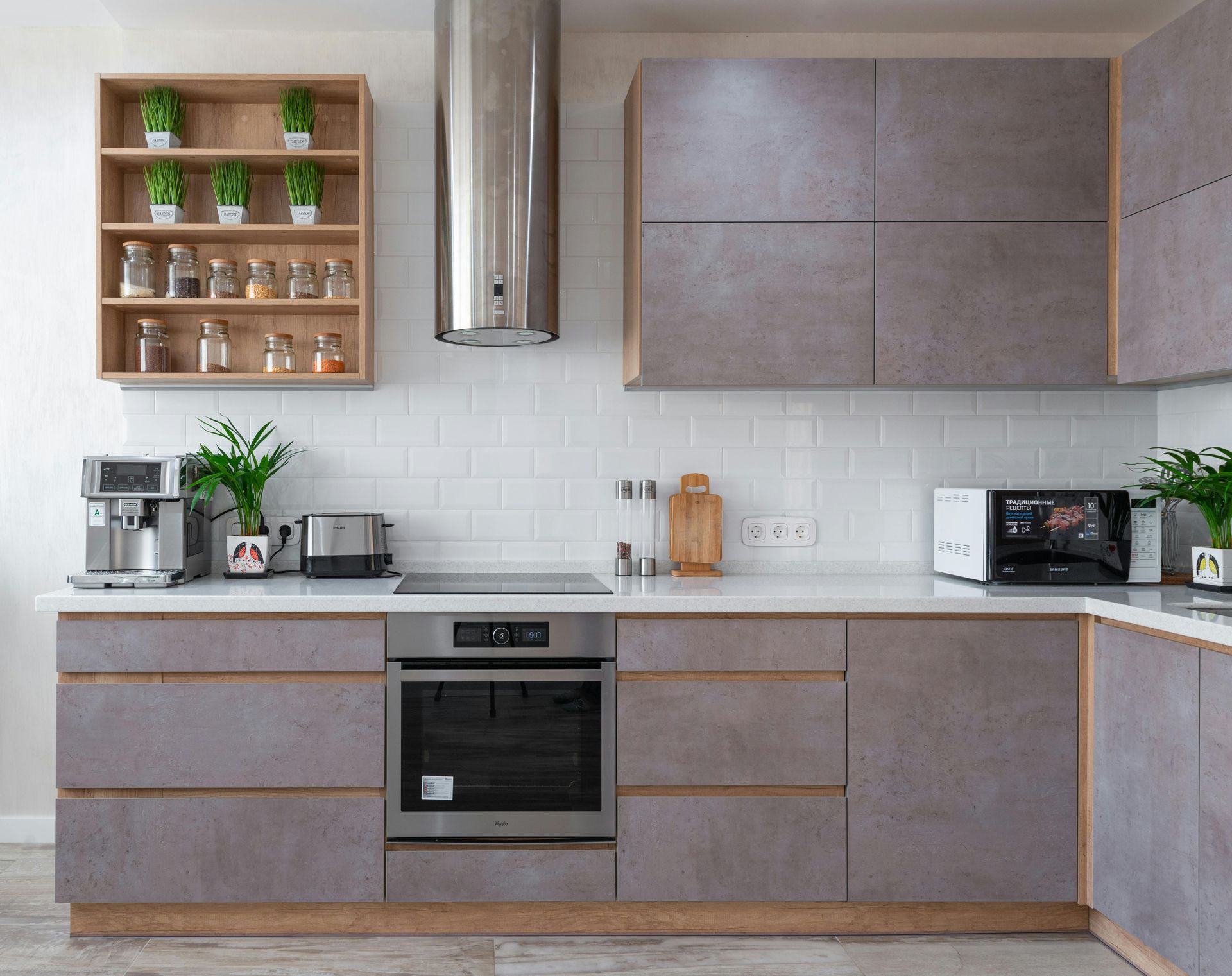 Modern kitchen with gray cabinets, stainless steel appliances, and wooden shelves with plants and spices.