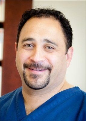Smiling healthcare worker in blue scrubs against a warm indoor background