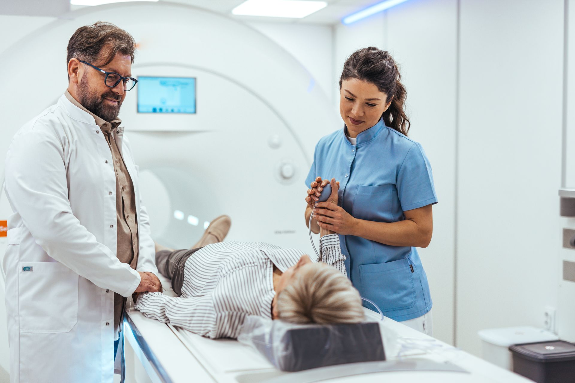Doctor and nurse assisting a patient undergoing a CT scan; hospital setting.