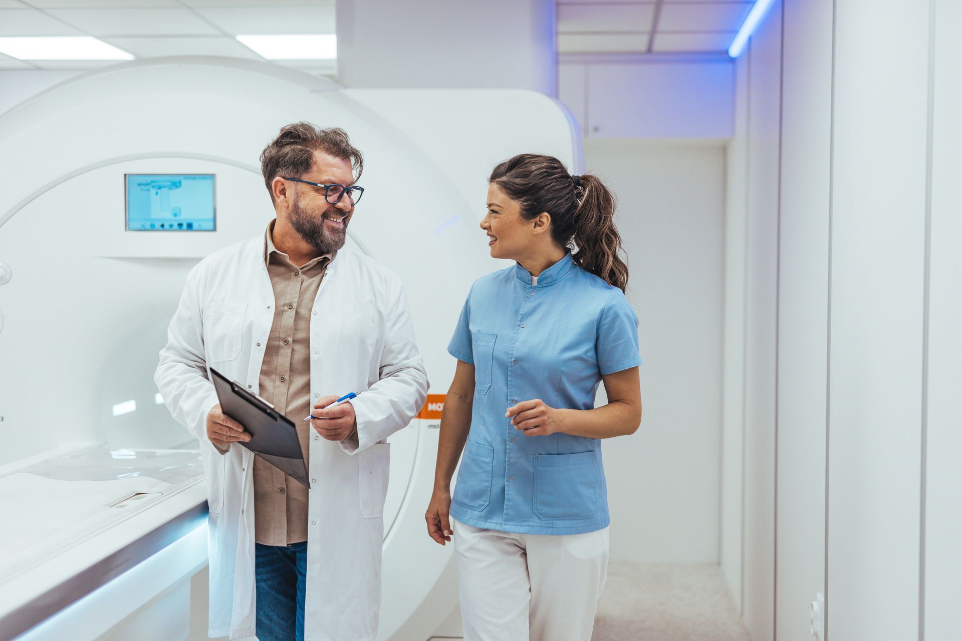 Doctor and nurse walking together in a bright hospital corridor, talking and smiling