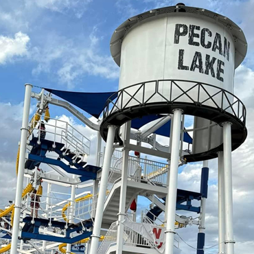 Water park tower with white tank labeled “PECA LAKE” and blue slides against a cloudy sky