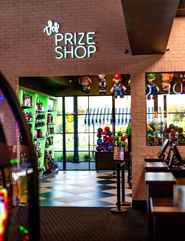 Interior of a bright arcade prize shop with colorful stuffed toys and shelves of prizes