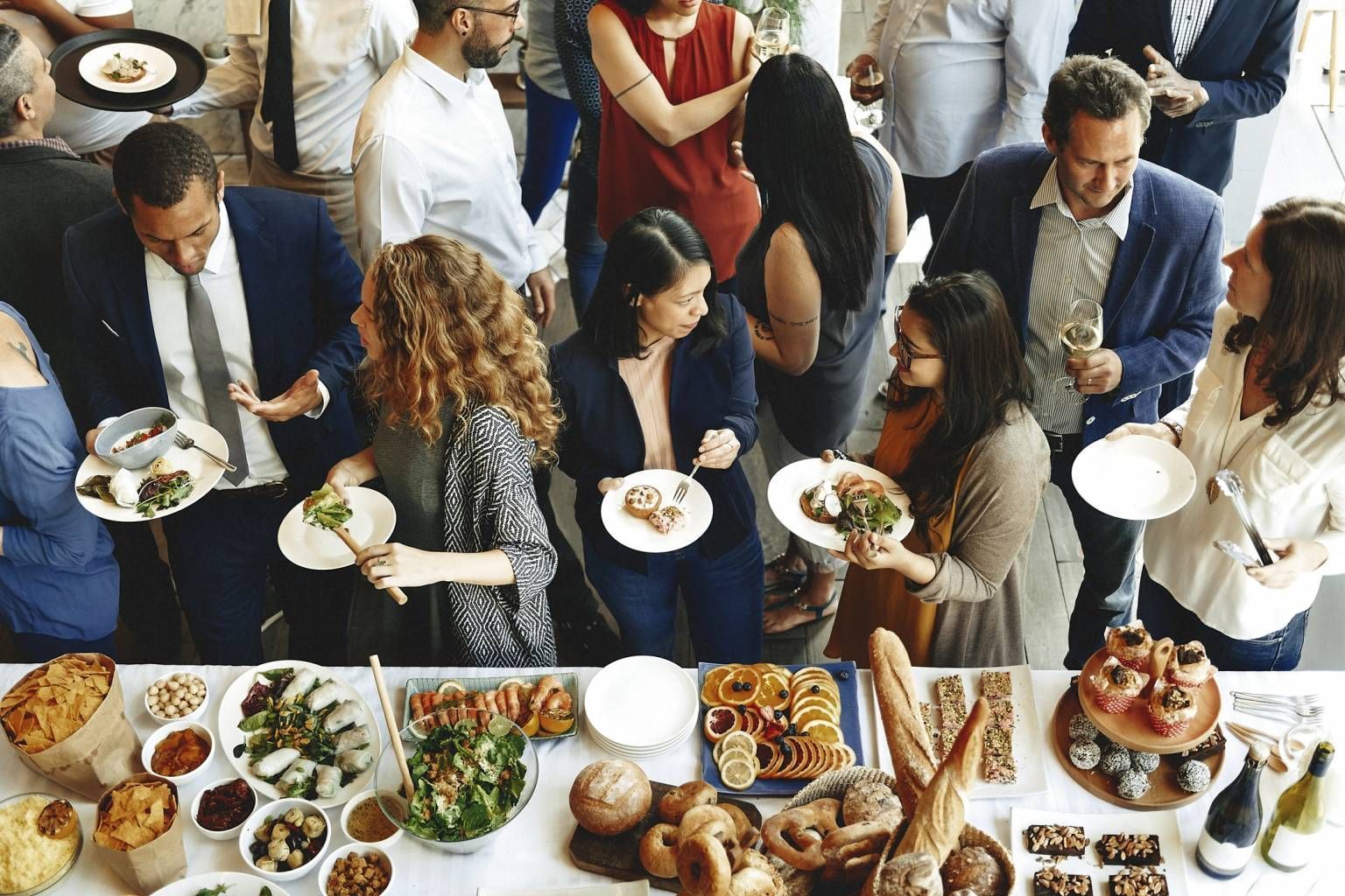 Guests serving themselves at a buffet table during a crowded indoor event