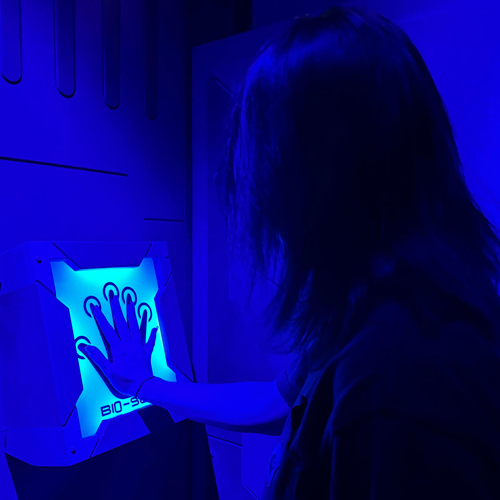 Person presses a glowing blue touch panel in a dark room