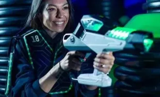 Smiling person aiming a futuristic white laser gun in a neon-lit sci-fi setting