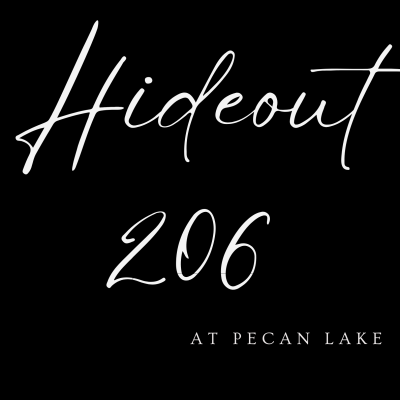 Black sign with white script text: “Hideout 206” and “at Pecan Lake”