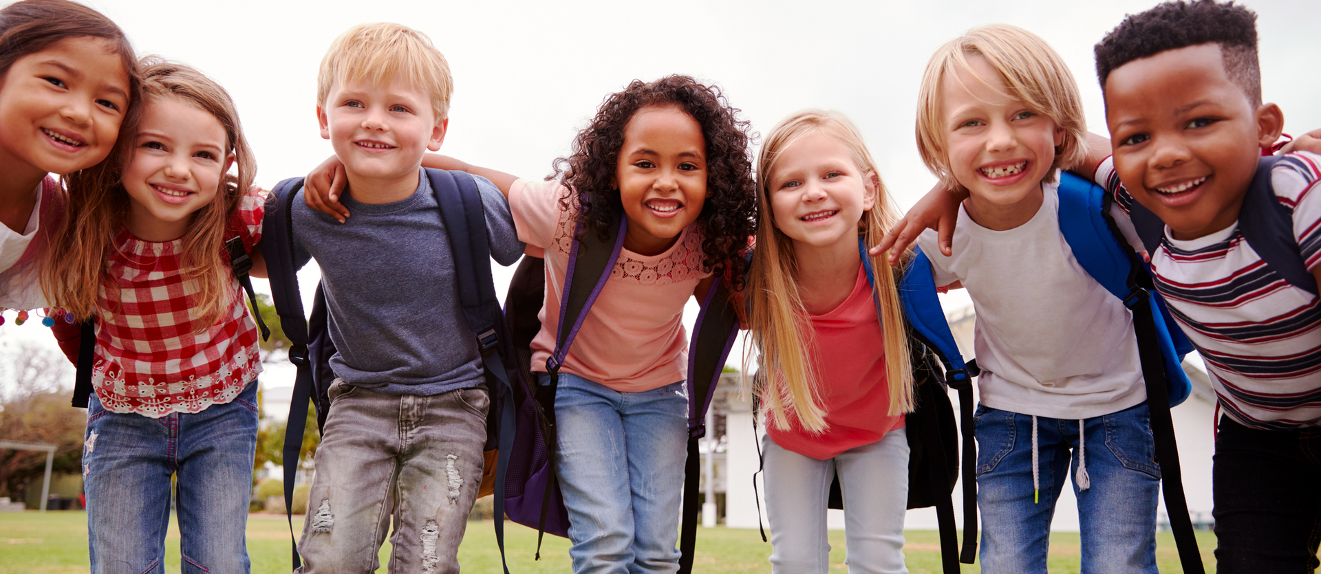 Group of smiling children leaning together outdoors on grass