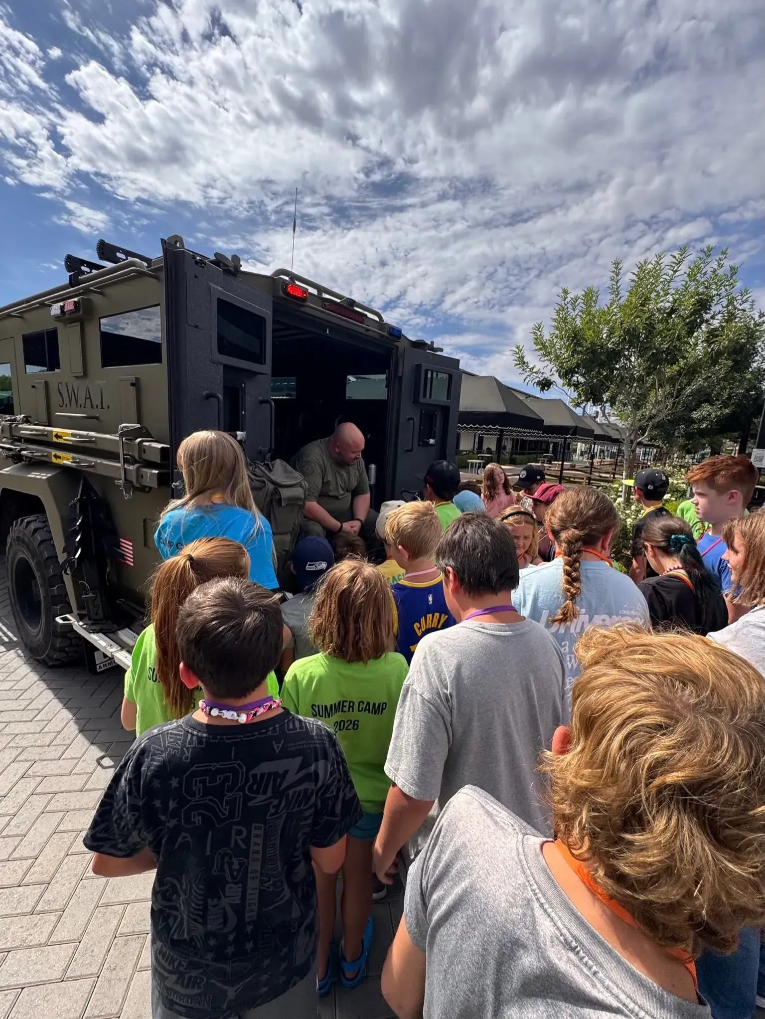 Students gathered around a S.W.A.T. vehicle during a summer camp group visit in Queen Creek, Arizona Students gathered around a S.W.A.T. vehicle during a summer camp group visit in Queen Creek, Arizona